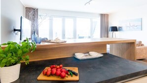 Eine moderne Küche mit einer Holzarbeitsplatte, einem Schneidebrett mit Tomaten und einer Topfpflanze.