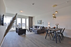 A modern living room with a sofa, dining table, chairs, and a large window.