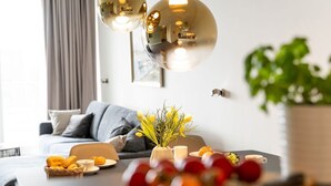 Een moderne eetruimte met een tafel voor twee personen, een bloevas en een schaal fruit.