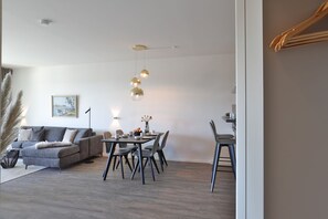A modern living room with a grey sofa, dining table, and chairs.