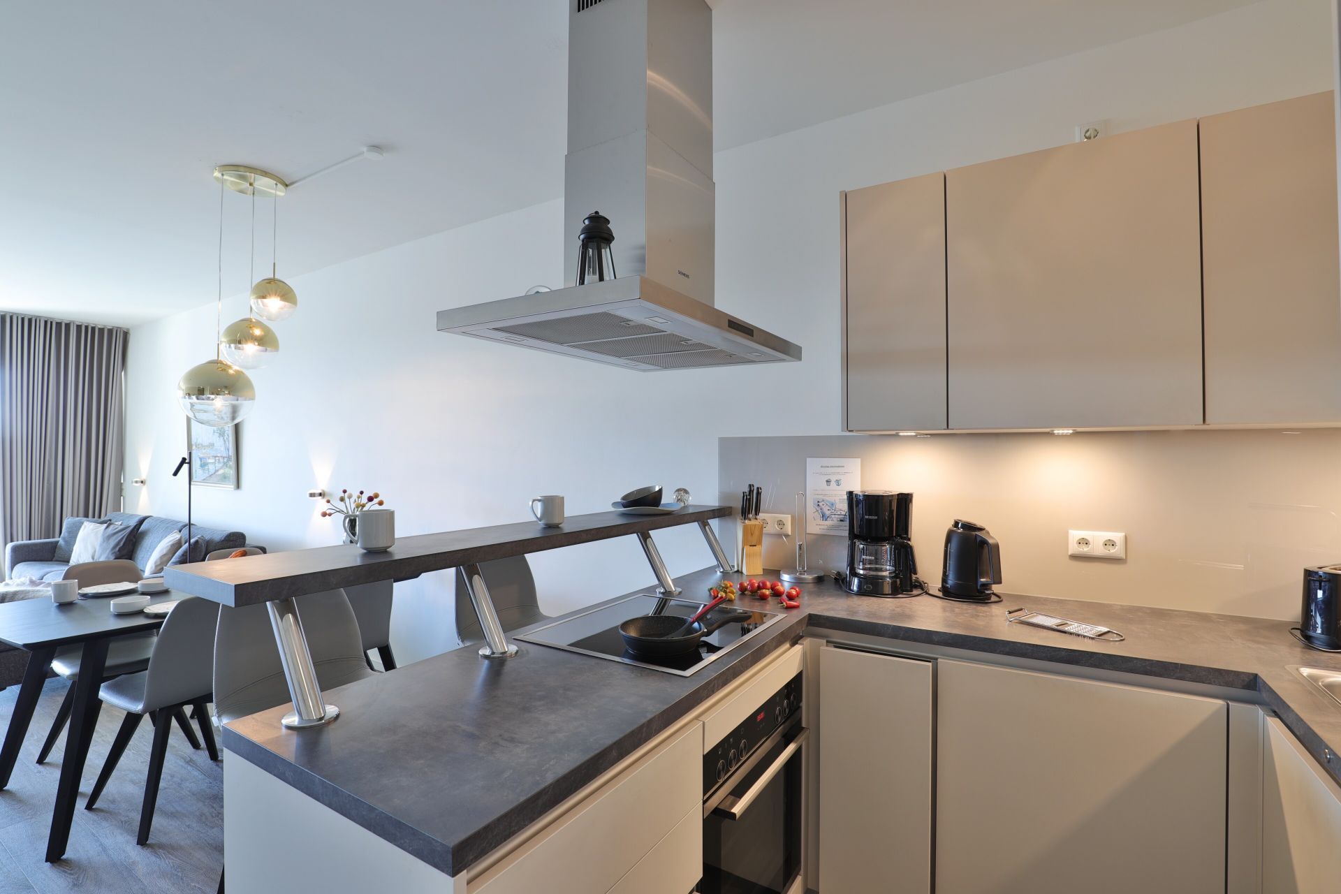 A modern kitchen with a central island, built-in oven, and stainless steel appliances.