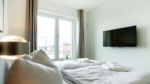 Een hotelkamer met een bed, een aan de muur bevestigde televisie en een raam met gordijnen.