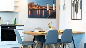 A modern kitchen with a dining area, featuring a wooden table, blue chairs, and pendant lights. - Hafenspitze App. 36, Deutschland (Wismar)