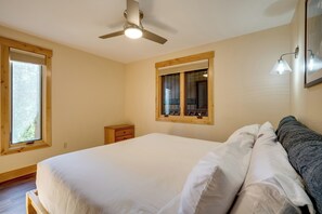 Ein Schlafzimmer mit einem großen Bett, einem Deckenventilator, einem Fenster, einem Nachttisch und einem Spiegel.