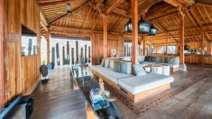 A spacious wooden interior with a large sofa, a dining area, and a kitchen. - Palatial Wooden Villa, 4br, Lovina (Banjar)