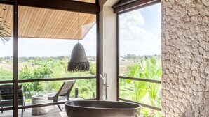 A modern bathroom with a freestanding bathtub, large windows, and a view of greenery. - Exceptional Architect's 5BR Villa, an Oasis Gem in Canggu Centre (Canggu)