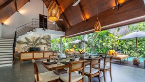 A spacious dining area with a high ceiling, wooden furniture, and a view of a lush garden and pool. - Contemporary Private Villa, 4 BR, Canggu With Staff (Canggu)