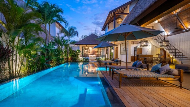 A luxurious pool area with a wooden deck, lounge chairs, and umbrellas. - Contemporary Private Villa, 4 BR, Canggu With Staff (Canggu)