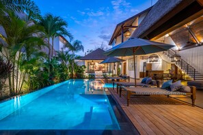 A luxurious pool area with a wooden deck, lounge chairs, and umbrellas. - Contemporary Private Villa, 4 BR, Canggu With Staff (Canggu)
