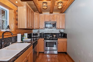 Une cuisine de taille réduite, dotée d’armoires en bois, d’appareils électroménagers en acier inoxydable et d’un plan de travail en granit.