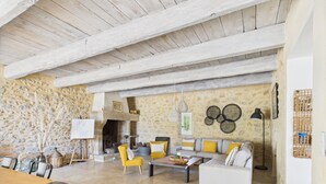 Amplia sala de estar con pared de piedra, chimenea y un conjunto de sofás.