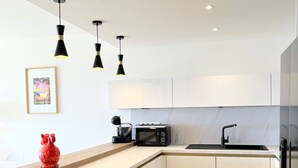 A modern kitchen with a wooden island, white cabinets, a black microwave, and a red decorative item. - Pierre Longue,3 bedrooms apartment with sea view in bulding with swimming pool (Cannes)
