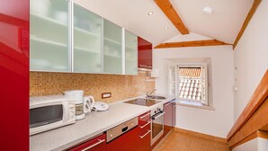 A modern kitchen with red cabinets, a microwave, a coffee maker, and a window with a view of the outside.