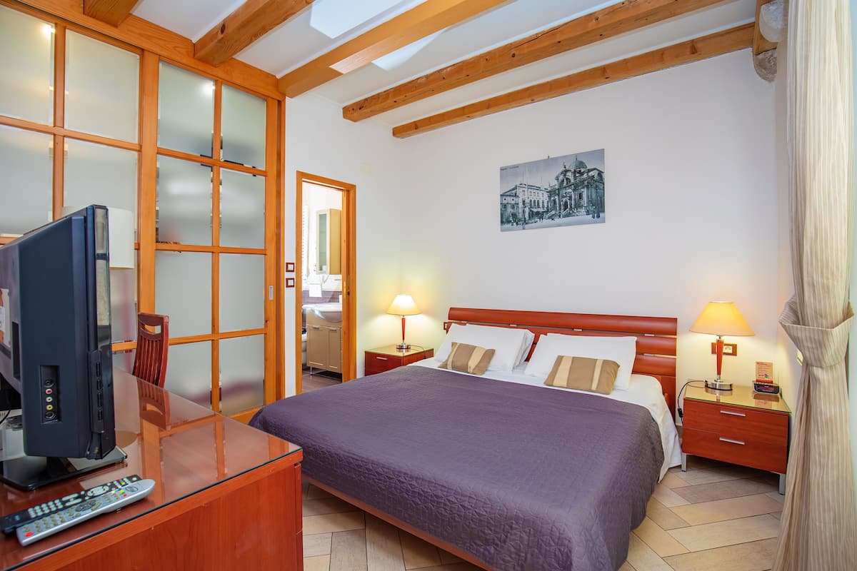 A hotel room with a bed, a TV, a desk, and a nightstand.
