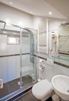 Um banheiro moderno com chuveiro envidraçado, vaso sanitário e pia.