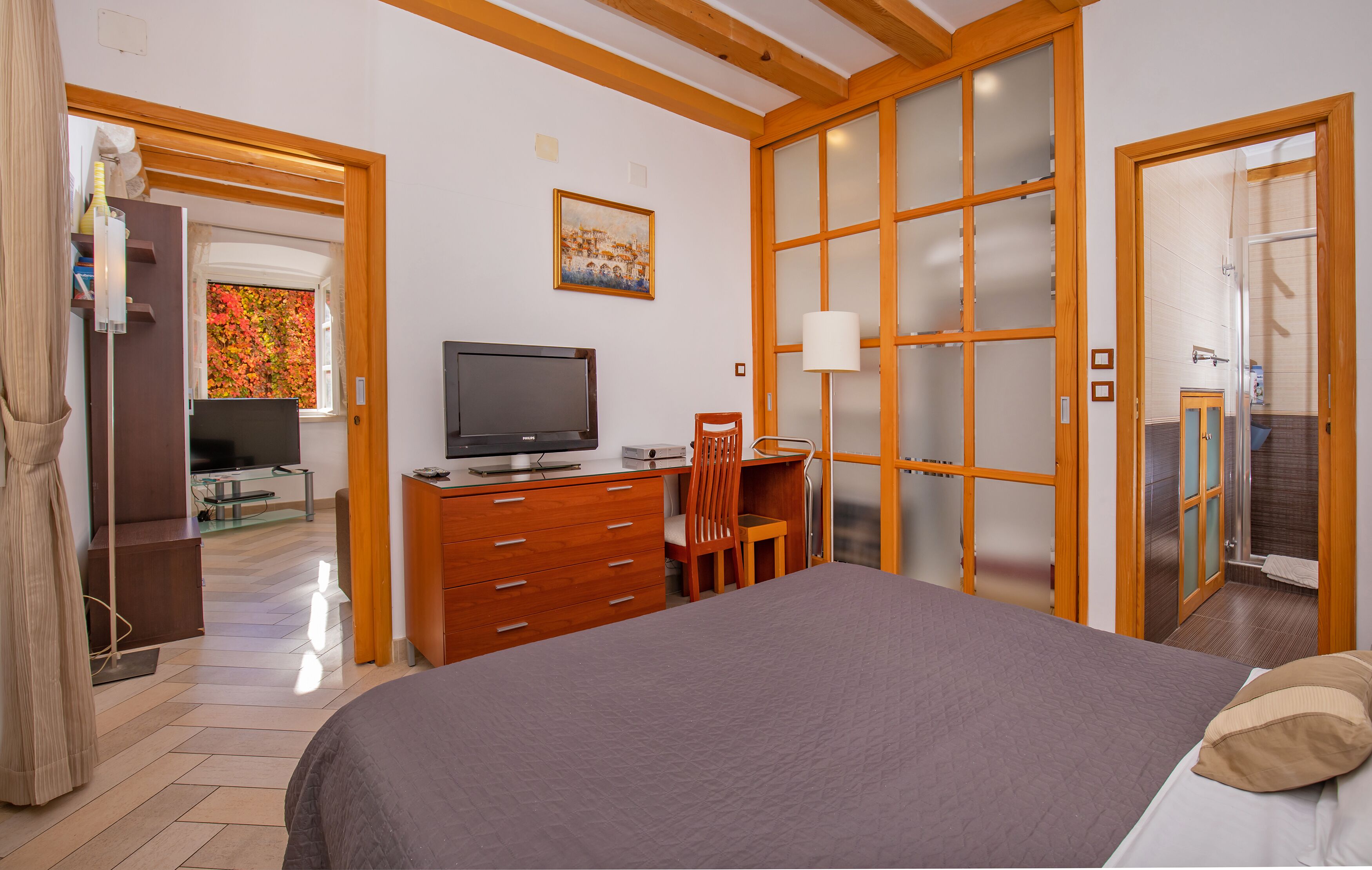 Un dormitorio con cama, escritorio, silla, televisor y armario.