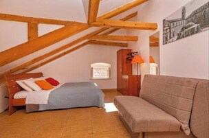 A bedroom with a bed, a sofa, a wardrobe, and a window.
