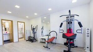 A gym with cardio machines, a bench press, and a mirrored wall.