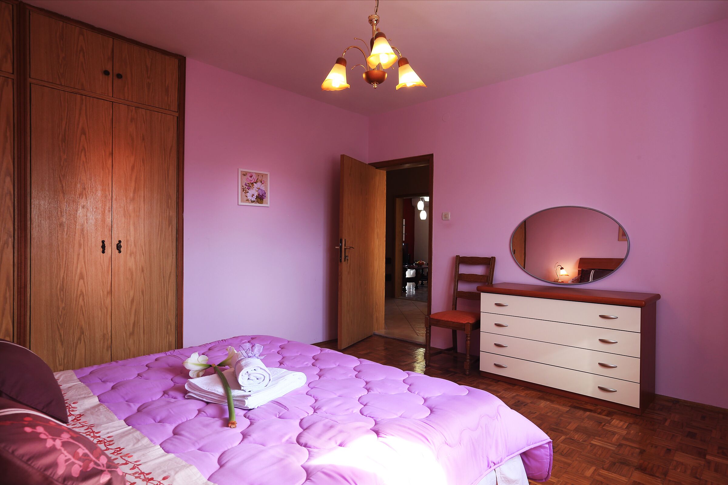 Un dormitorio con cama, armario de madera, cómoda y espejo.