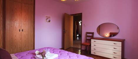Un dormitorio con cama, armario de madera, cómoda y espejo.