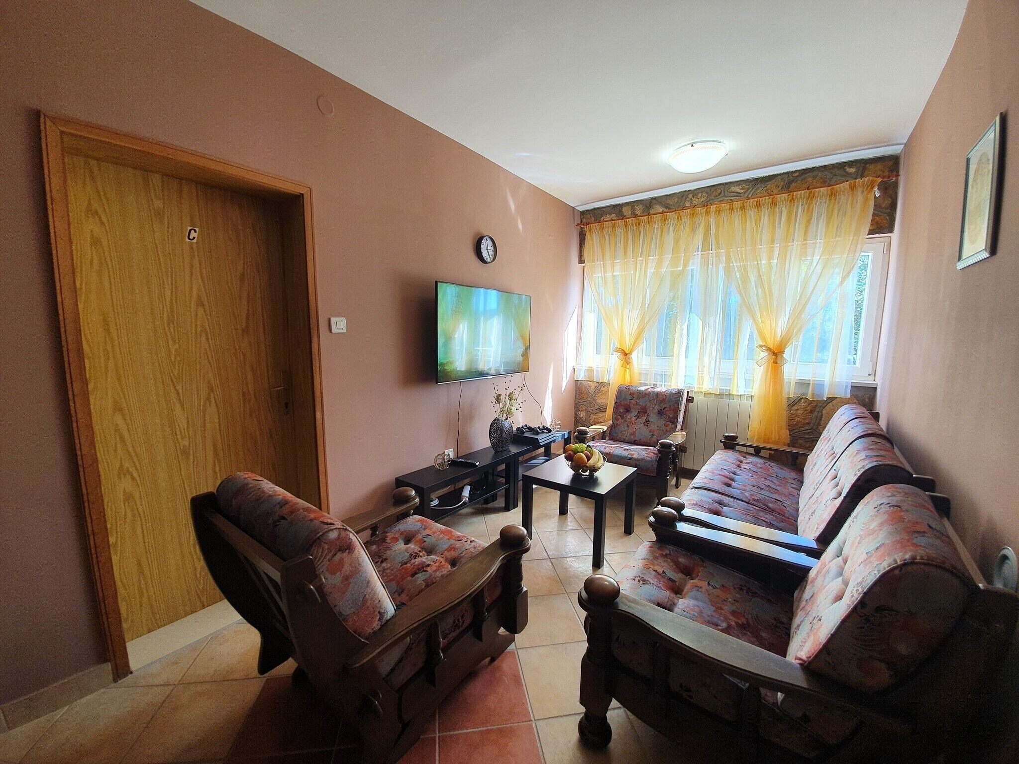 A living room with a sofa set, a television, and a wooden door.