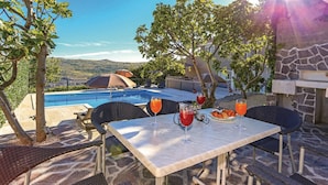 A poolside dining area with a table, chairs, and two drinks.