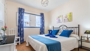 A bedroom with a bed, a desk, a chair, and a window with curtains. - Holiday Home "El Sombrerito 5" with Terrace & Wi-Fi (Caleta de Sebo)