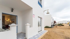 A white building with a tiled entrance, a door, and a window with a blue frame. - Holiday Home "El Sombrerito 4" with Terrace & Wi-Fi (Caleta de Sebo)