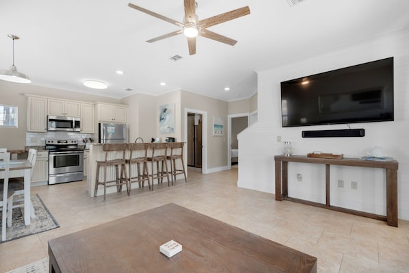 A modern kitchen with white cabinets, stainless steel appliances, and a dining area with wooden chairs.