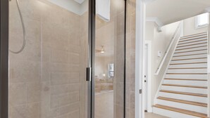 Een moderne badkamer met een douchecabine van glas, een houten trap en een zichtbaar badkamermeubel.