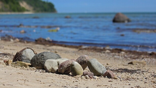 Ein Strand mit Felsen und einer entfernten Küstenlinie.