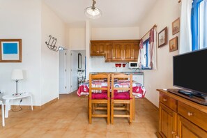 Un espace de vie compact comprenant un coin repas, une kitchenette et un téléviseur.