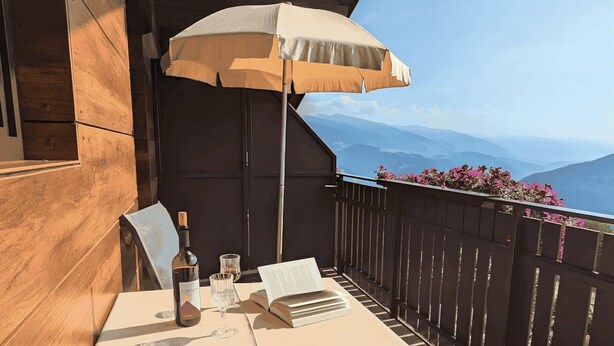 A balcony with a table, a bottle, a glass, and an open book.