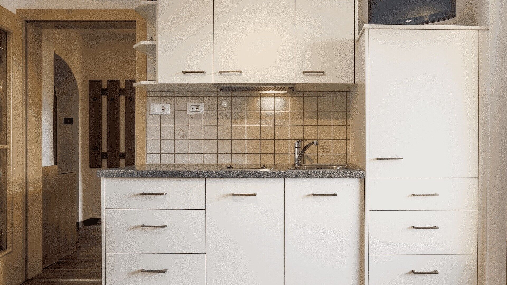 Eine moderne Küche mit weißen Schränken, einer Granit-Arbeitsplatte und einer eingebauten Mikrowelle.
