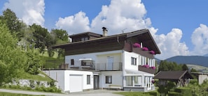 A two-story house with a balcony, a garage, and a view of mountains.