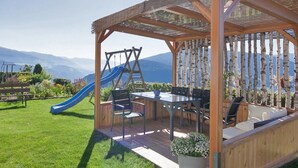 A wooden gazebo with a slide, outdoor seating, and a view of mountains.