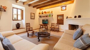 Ein Wohnzimmer mit Kamin, Holzbalken, Fernseher und Bücherregal.