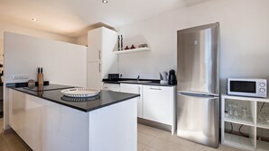 A modern kitchen with a central island, stainless steel appliances, and white cabinetry. - Apartment “La Casita” with Sea View, Pool, Wi-Fi, Terrace & Balcony (Adeje)