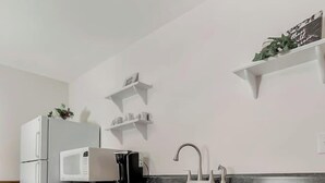 Una cocina moderna con armarios blancos, microondas, cafetera y un lavabo.