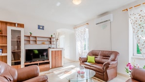 A modern living room with a leather sofa, a glass coffee table, and a flat-screen TV.