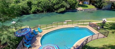 A swimming pool with a surrounding deck, a slide, and a view of a river.