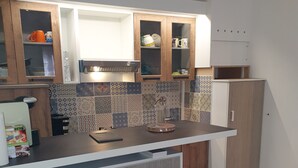 Une cuisine moderne dotée d’un îlot central, de deux tabourets de bar et de différents types de meubles de rangement.