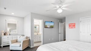 A bedroom with a large bed, a ceiling fan, a TV, and a door with a beach-themed sign. - Walk to Surfside Beach from This 4-Bedroom Condo w/ Resort Pool (Surfside Beach)