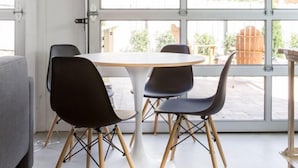 A modern dining area with a round table and two chairs, large windows, and a view of the outside.