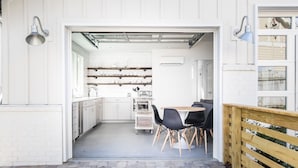 A modern kitchen with white cabinets, a dining area with black chairs, and a wooden fence.