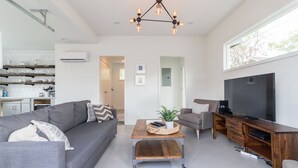 A modern living room with a grey sofa, a coffee table, a TV, and a wooden cabinet.