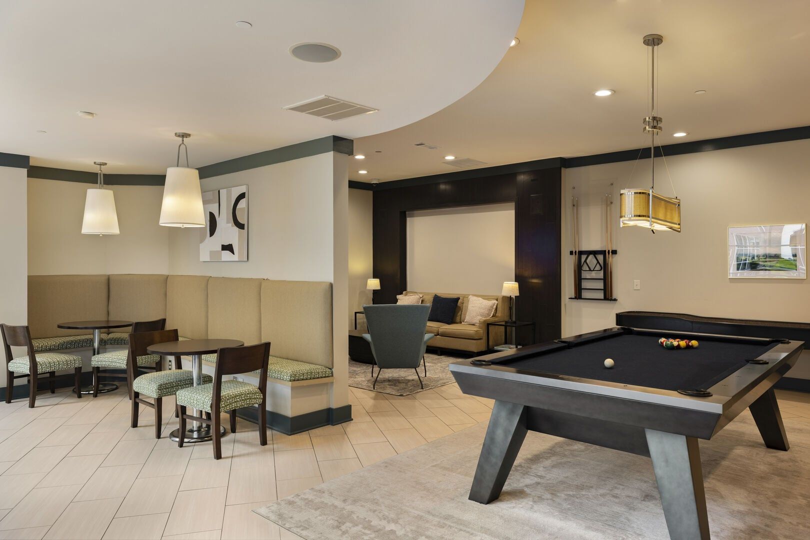 Une table de billard dans une pièce où se trouvent un canapé, des fauteuils et une table à manger.