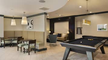 A pool table in a room with a sofa, chairs, and a dining table.
