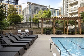 A poolside area with lounge chairs and a pergola.