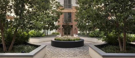 A courtyard with a central planter, surrounding brick walls, and trees.